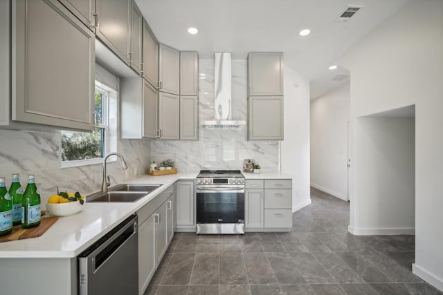kitchen with a sink, appliances with stainless steel finishes, wall chimney exhaust hood, and gray cabinets