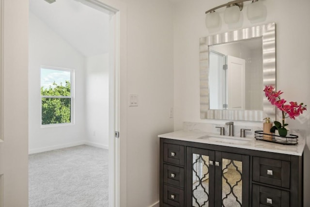 bathroom featuring baseboards, lofted ceiling, and vanity
