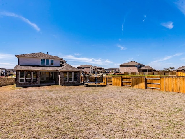 110 Pigeon River Rd, Kyle, TX 78640 - back of property featuring brick siding, a trampoline, a shingled roof, and a residential view