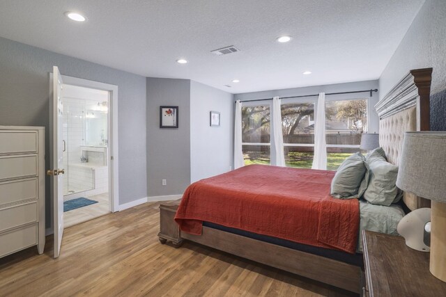 30228 Saint Andrews Dr, Georgetown, TX 78628 - bedroom with light wood-style flooring, recessed lighting, connected bathroom, and a textured ceiling
