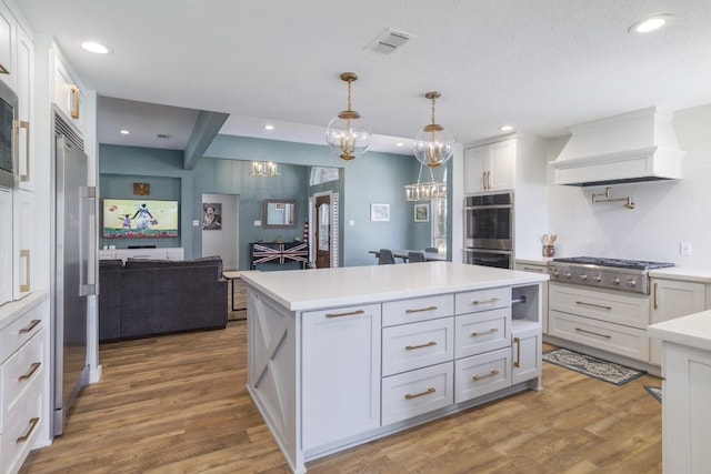 30228 Saint Andrews Dr, Georgetown, TX 78628 - kitchen with appliances with stainless steel finishes, custom range hood, light countertops, white cabinetry, and wood finished floors