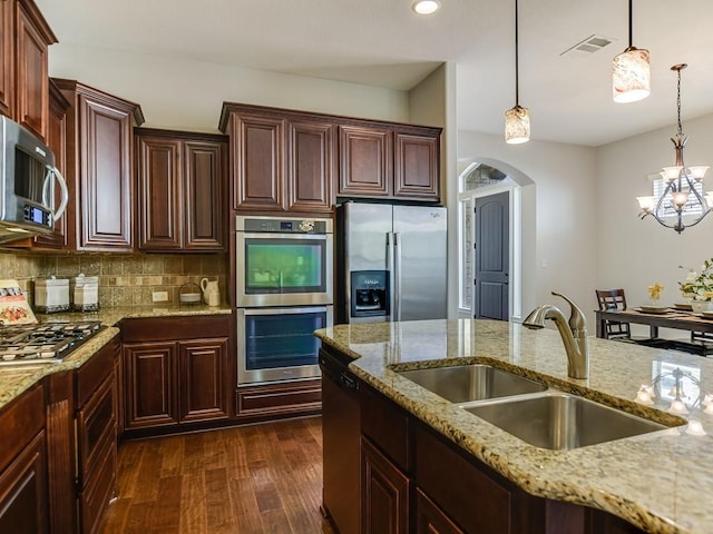 15218 Glen Heather Dr, Lakeway, TX 78734 - kitchen with appliances with stainless steel finishes, arched walkways, dark wood-type flooring, pendant lighting, and a chandelier