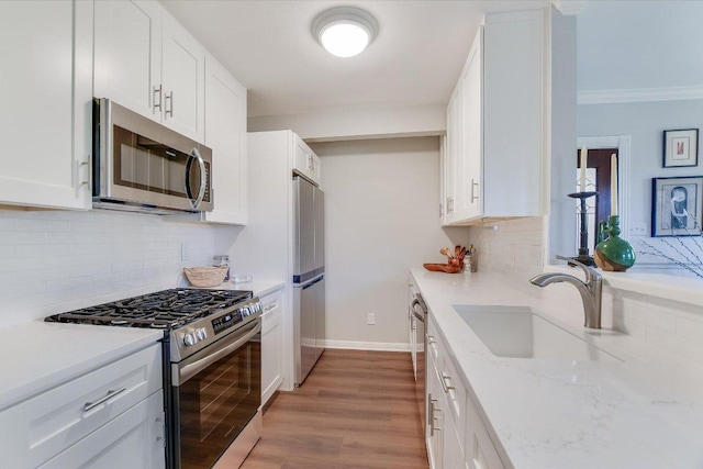 4010 Lewis Ln, Austin, TX 78756 - kitchen with appliances with stainless steel finishes, a sink, backsplash, white cabinetry, and light wood-type flooring