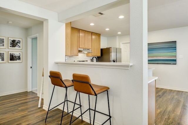 837 Watson Way, Pflugerville, TX 78660 - kitchen with stainless steel fridge, under cabinet range hood, dark wood-style flooring, a kitchen breakfast bar, and decorative backsplash