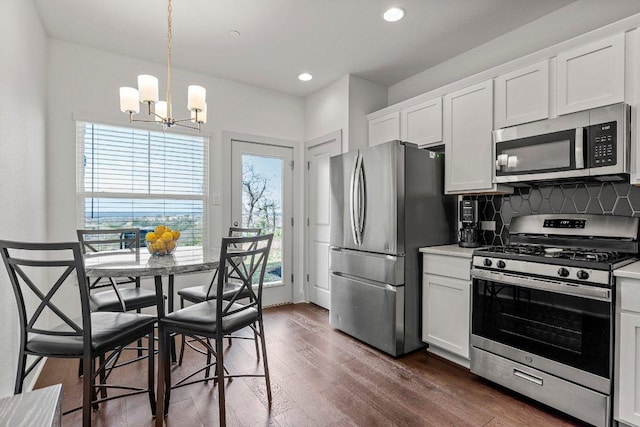 2256 Local Rebel Loop, Leander, TX 78641 - kitchen with appliances with stainless steel finishes, a chandelier, dark wood-style floors, decorative backsplash, and white cabinetry