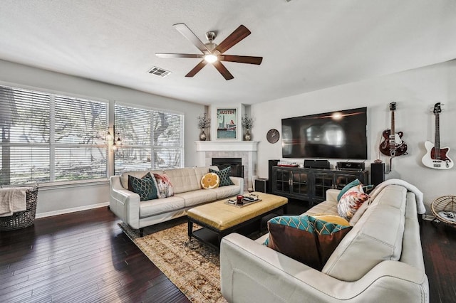 living room with dark wood finished floors, a tile fireplace, visible vents, baseboards, and ceiling fan