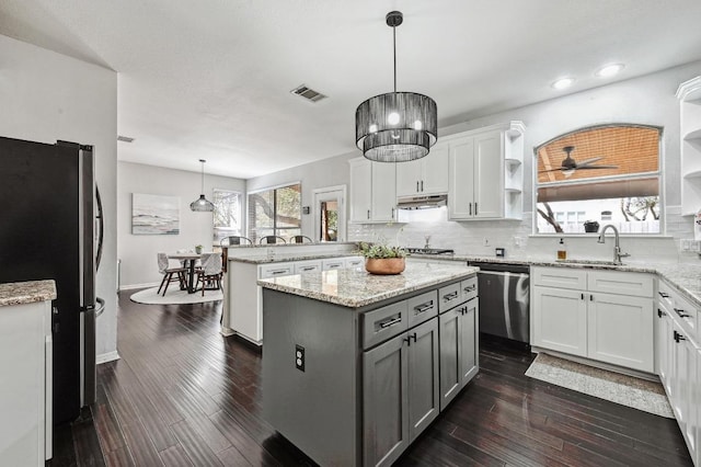 kitchen featuring under cabinet range hood, open shelves, visible vents, a peninsula, and appliances with stainless steel finishes