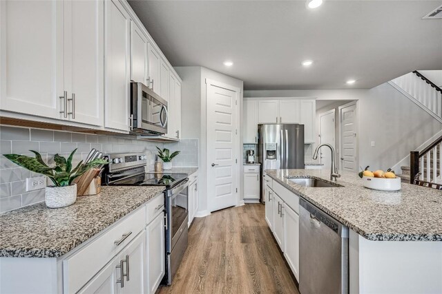 329 Peace Pipe Way, Georgetown, TX 78628 - kitchen featuring appliances with stainless steel finishes, a sink, wood finished floors, white cabinets, and recessed lighting