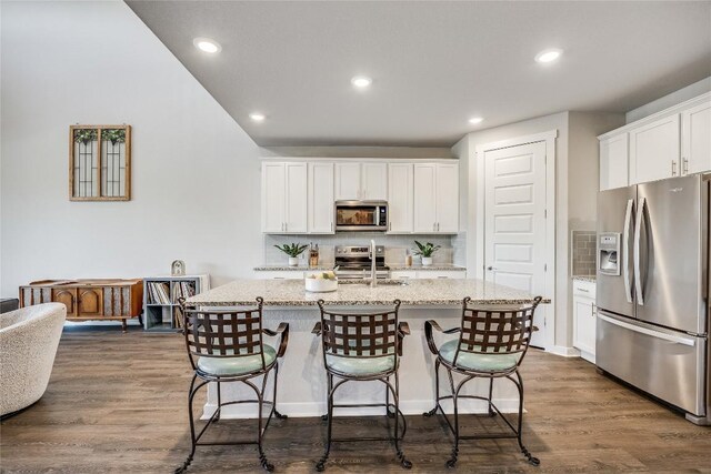 329 Peace Pipe Way, Georgetown, TX 78628 - kitchen featuring stainless steel appliances, decorative backsplash, white cabinetry, a kitchen bar, and recessed lighting