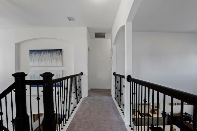 corridor featuring visible vents, carpet floors, and an upstairs landing