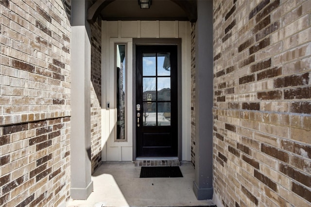 view of exterior entry featuring board and batten siding and brick siding