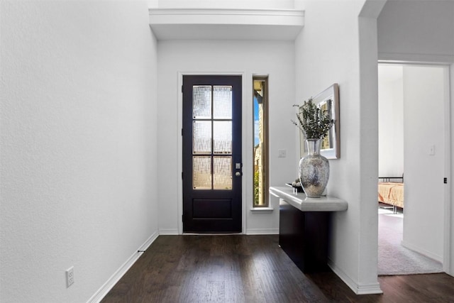 entrance foyer featuring baseboards, arched walkways, and dark wood-style floors