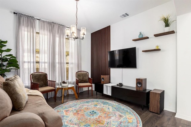 living area featuring a notable chandelier, visible vents, baseboards, and wood finished floors