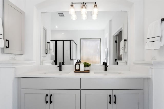 full bath with double vanity, visible vents, a sink, and a stall shower