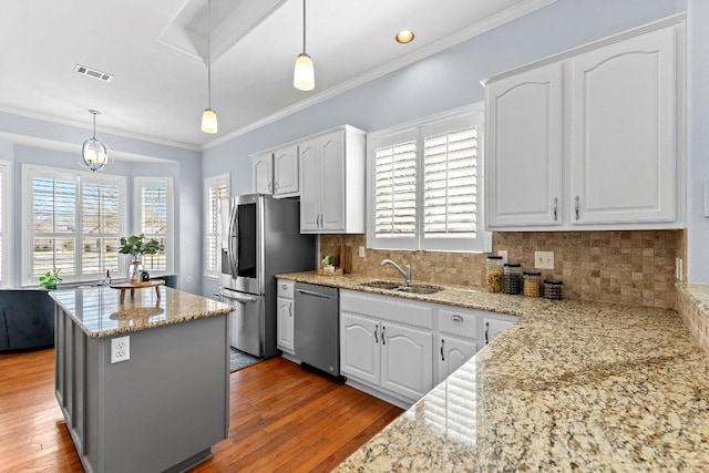 100 Blacksmiths Cir, Georgetown, TX 78633 - kitchen featuring stainless steel appliances, light stone countertops, white cabinets, wood finished floors, and ornamental molding