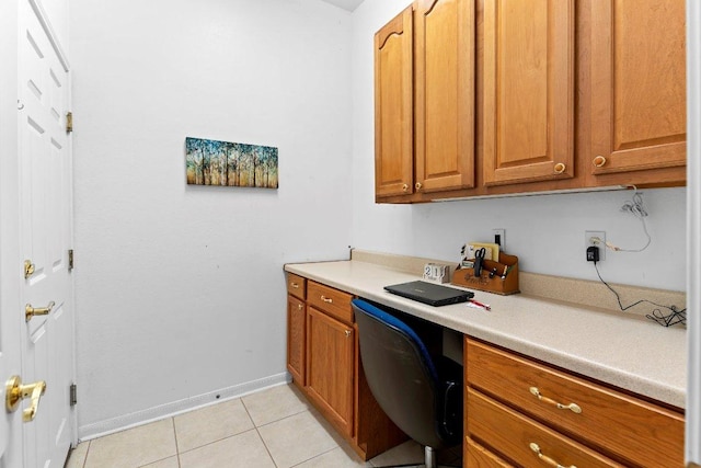 100 Blacksmiths Cir, Georgetown, TX 78633 - kitchen featuring built in desk, light tile patterned floors, light countertops, and brown cabinetry