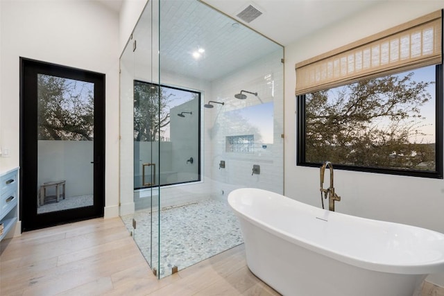 5805 Twin Peaks Trce, Austin, TX 78738 - full bathroom featuring a freestanding bath, a shower stall, and wood finished floors
