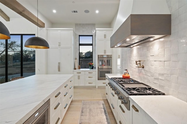 5805 Twin Peaks Trce, Austin, TX 78738 - kitchen featuring wall chimney exhaust hood, stainless steel appliances, backsplash, white cabinets, and plenty of natural light