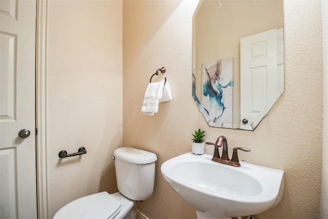half bathroom featuring toilet and a sink