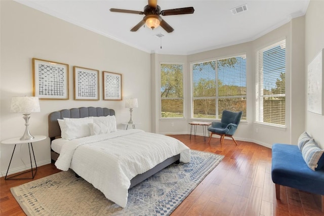 bedroom featuring crown molding, wood finished floors, baseboards, and ceiling fan