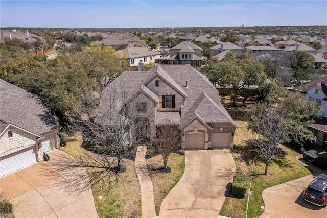 view of front of property with stone siding, a garage, concrete driveway, and a residential view