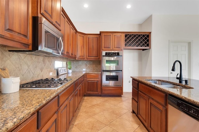 4004 Buckhaven Cv, Cedar Park, TX 78613 - kitchen with stainless steel appliances, decorative backsplash, light stone counters, brown cabinetry, and recessed lighting