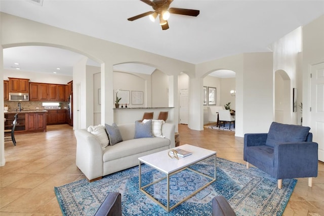 living room featuring a ceiling fan, light tile patterned floors, arched walkways, baseboards, and recessed lighting