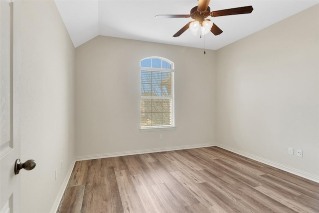 empty room featuring wood finished floors, ceiling fan, baseboards, and lofted ceiling
