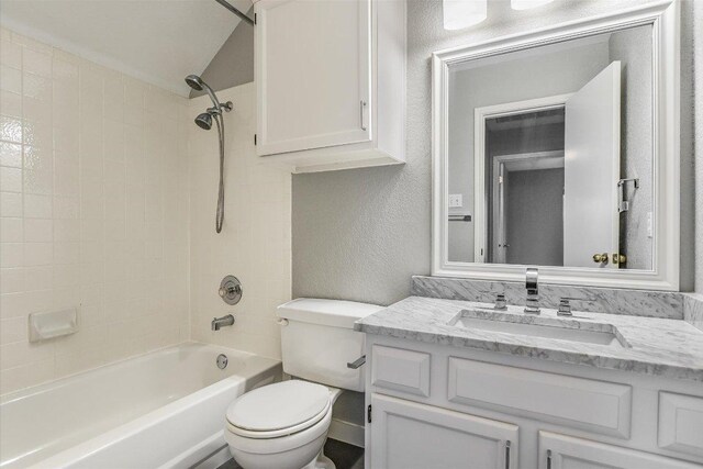 full bathroom with vaulted ceiling, vanity, toilet, washtub / shower combination, and a textured wall