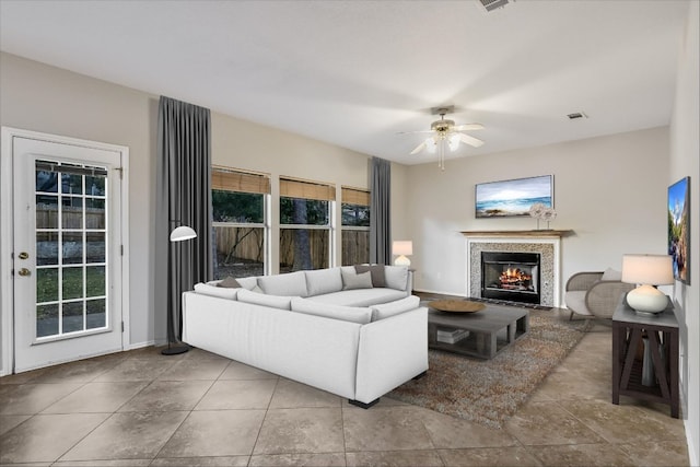 living area with visible vents, baseboards, ceiling fan, tile patterned floors, and a fireplace with flush hearth