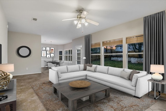 tiled living area featuring baseboards, ceiling fan, and visible vents