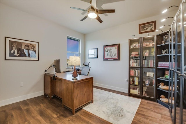 office area featuring dark wood-type flooring, a ceiling fan, and baseboards