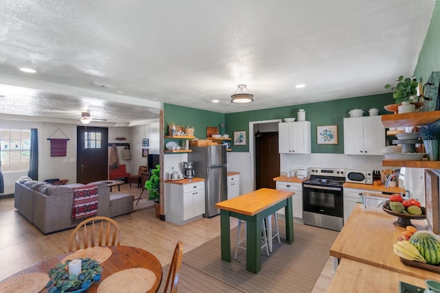 130 Holbox Dr, Del Valle, TX 78617 - kitchen with appliances with stainless steel finishes, wood counters, open shelves, white cabinetry, and recessed lighting