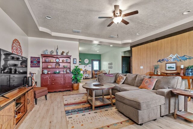 130 Holbox Dr, Del Valle, TX 78617 - living room with a textured ceiling, ceiling fan, wood finished floors, and a tray ceiling