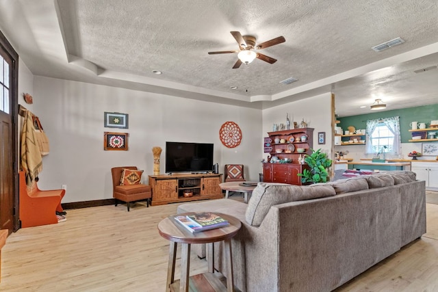 130 Holbox Dr, Del Valle, TX 78617 - living area featuring a textured ceiling, light wood finished floors, a raised ceiling, and ceiling fan