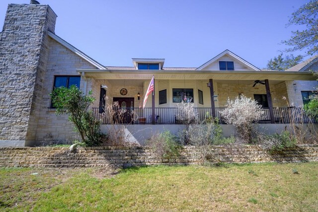 22207 Moulin Dr, Spicewood, TX 78669 - view of front of house with a porch, a front lawn, a chimney, and stone siding