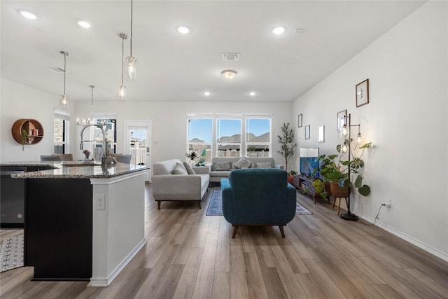 living area with recessed lighting, visible vents, baseboards, and wood finished floors