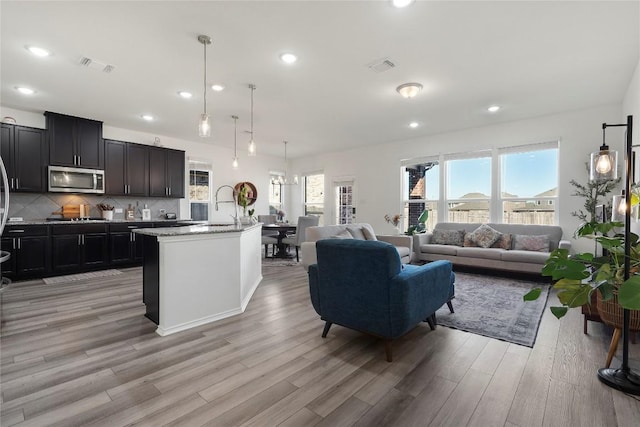 living area with a wealth of natural light, visible vents, and light wood-style flooring