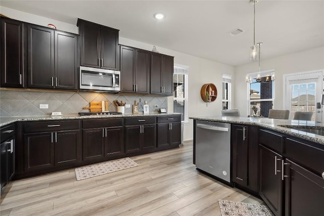 kitchen with light stone countertops, visible vents, an inviting chandelier, stainless steel appliances, and tasteful backsplash