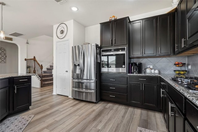 kitchen featuring light wood-type flooring, stainless steel appliances, and dark cabinetry