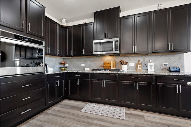1128 Hemlen Cv, Leander, TX 78641 - kitchen with appliances with stainless steel finishes, decorative backsplash, and light stone counters