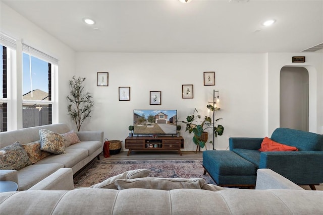 living room with arched walkways, visible vents, recessed lighting, and wood finished floors