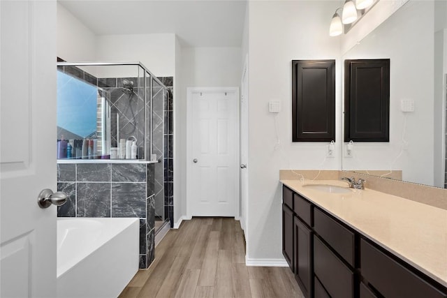 full bathroom featuring a stall shower, wood finished floors, baseboards, a bath, and vanity