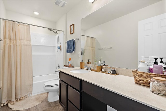 bathroom with visible vents, shower / bath combo with shower curtain, toilet, wood finished floors, and vanity