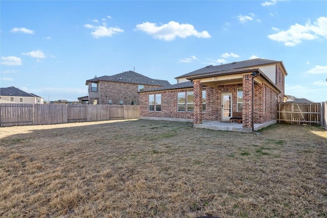 back of property with brick siding, a lawn, a patio, and a fenced backyard