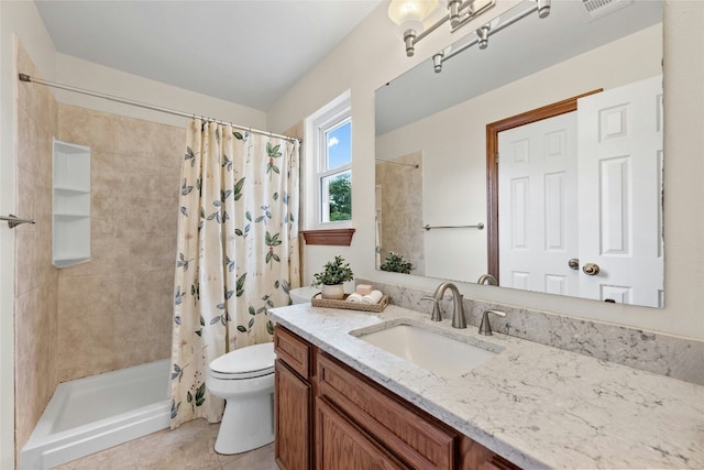 bathroom featuring tile patterned floors, vanity, a tile shower, and toilet