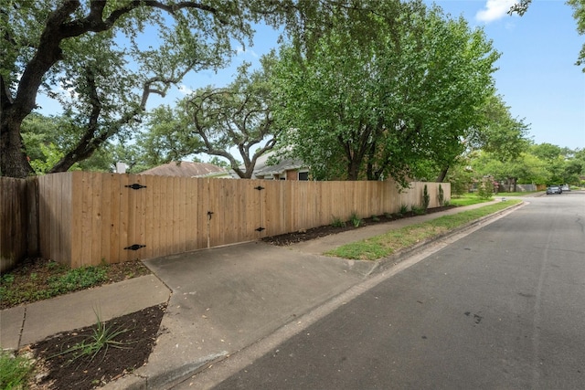 view of road featuring sidewalks, curbs, and a gate