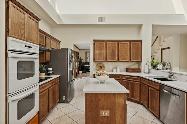 kitchen with visible vents, a kitchen island, appliances with stainless steel finishes, light countertops, and a sink