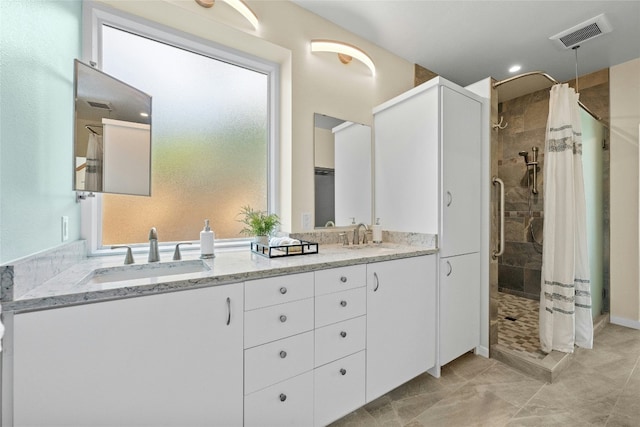 full bath with tiled shower, double vanity, a sink, and visible vents