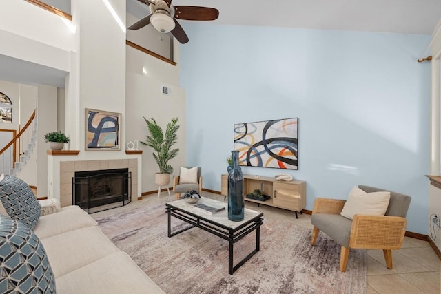 tiled living room with baseboards, a ceiling fan, stairs, visible vents, and a tile fireplace